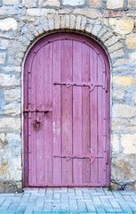 Ancient wooden door in old stone wall.