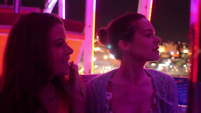 Two friends on a ferris wheel at night
