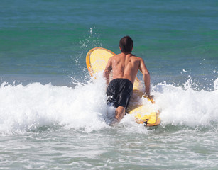 Surfer on longboard rides a wave in the sea