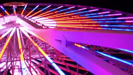 Angle from below of a ferris wheel lit up at night
