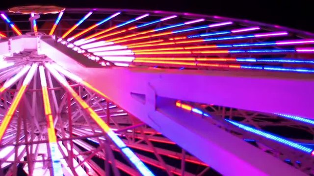 Angle from below of a ferris wheel lit up at night

