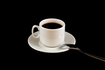 cup of coffee on a saucer with a spoon on a black background