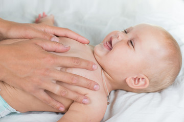 Obraz na płótnie Canvas Baby massage. Mother massaging infant belly, kid laughing