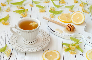 Cup of herbal tea with linden flowers, lemon and honey on a old wooden background