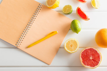 citrus with notebook on white wooden table