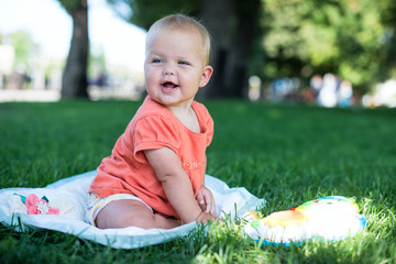 Summer portrait of beautiful baby girl sitting in grass