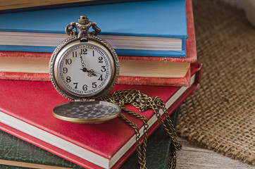 pocket or pendant watch on background of old books