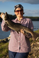 Woman caught a big beautiful salmon. Self portrait. Kola Peninsula, Russia.