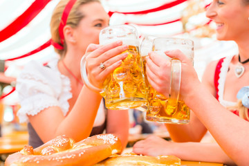 Freundinnen trinken zusammen Bier im Bayrischen Dirndl auf Volksfest