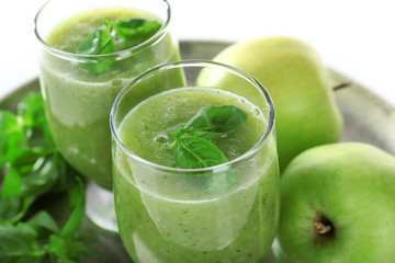Glasses of green healthy juice with basil and apples on metal tray close up