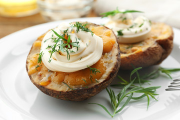 Baked potato with mayonnaise and herbs in white plate, closeup