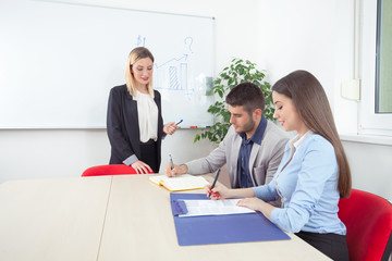 Young business people writing notes on a training class or seminar in a conference room