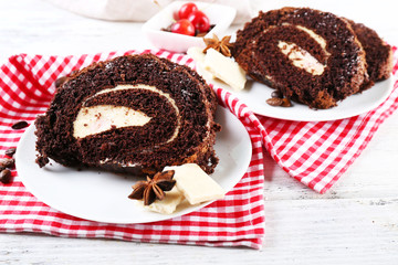 Delicious chocolate roll in white saucer on checkered napkin, closeup