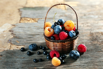 Sweet tasty berries in basket on wooden table close up