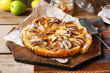 Homemade apple pie on cutting board on wooden background