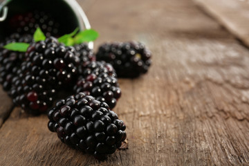 Ripe blackberries with green leaves on wooden table, closeup