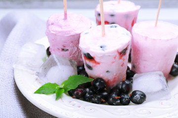 Sweet ice cream with black currants in white plate on grey napkin, closeup