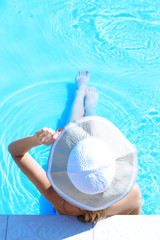 Woman in hat resting in swimming pool
