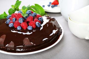 Delicious chocolate cake with summer berries on grey tablecloth, closeup