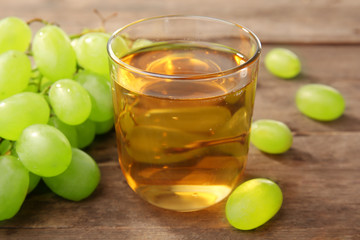 Glass of grape juice on wooden table, closeup