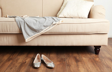Fototapeta na wymiar Female dress on sofa near shoes on floor in room