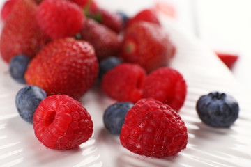 Tasty ripe berries on plate close up