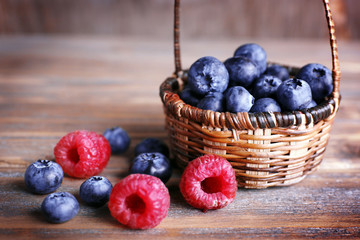 Tasty ripe berries in basket on wooden table close up
