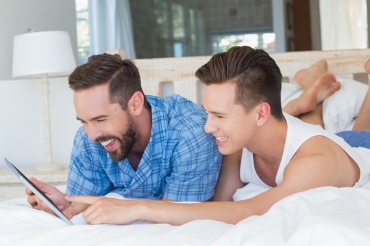 Happy homosexual couple looking at tablet computer 