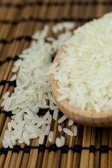 Rice in wooden spoon on traditional Asian plate mat