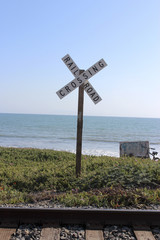 Rail Road Crossing Sign with Tracks, Ocean and Blue Sky