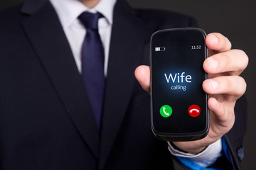 male hand holding smart phone with incoming call from wife