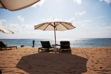 Sun umbrella and beach beds on tropical beach. Bali, Indonesia.