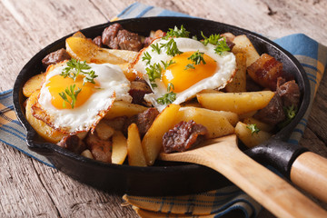 European cuisine: fried potatoes with meat, bacon and eggs in a pan 
