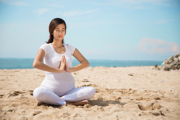 Fototapeta na wymiar pregnant woman doing yoga in the beach