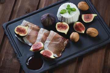 Basalt plate with ricotta cheese, ham, fresh figs and walnuts