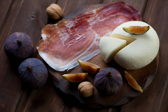 Sliced adygea cheese with figs, ham and walnuts, selective focus