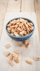Salted peanuts blue ceramic bowl on a wooden floor