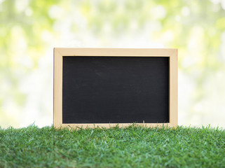 Mini black chalkboard on green grass