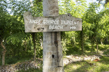 Wood sign.Trail to the tropical beach Source D'Argent at island La Digue, Seychelles. It is one of the best tropical beaches in the world, with big boulders granite rocks and turquoise water. 