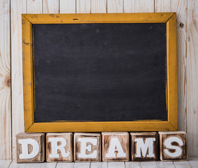 Chalkboard and DREAMS sign made of wooden blocks on wooden backg