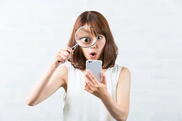 Fotobehang スマホを虫眼鏡で見る女性 © kei907