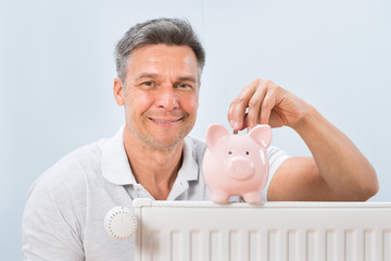 Man Inserting Coin In Piggy Bank
