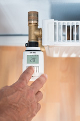 Person's Hand Adjusting Temperature On Thermostat