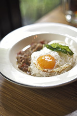 Fried egg on fired chilli beef with herb (Selective focus)