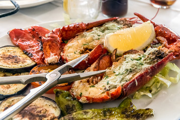  Plate with grilled lobster on the sliced vegetables and lemon in the centre.
