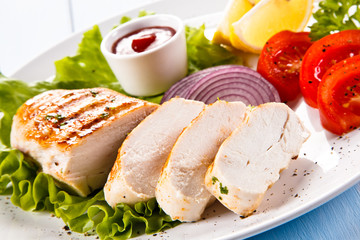 Grilled chicken fillet and vegetables on white background 