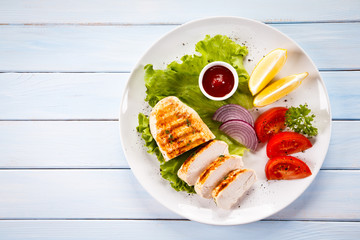 Grilled chicken fillet and vegetables on white background 