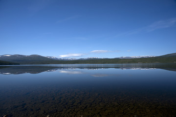 Fototapeta na wymiar Tranquil lake with snow covered mountains, Norway