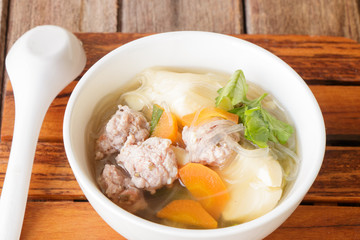 clear soup with pork in white plate put on wooden background, Thai cuisine.