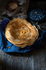 Blintzes or blini - thick russian crepes served with blueberries on dark wooden table. Rustic still life